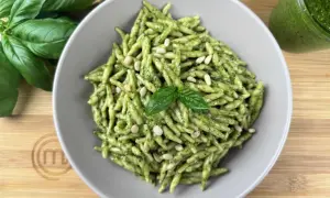 Piatto di trofie al pesto, guarnite con pinoli e basilico fresco. Un classico delle trofie ricette, pronto da gustare.