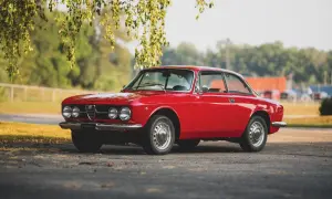 Klasyczny czerwony Alfa Romeo GT 1300 Junior, jeden z pięknych alfa romeo modele, stoi pod drzewem.