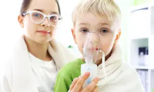Dziecko z nebulizatorem i dziewczynka w okularach.