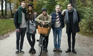Pięcioro przyjaciół w jesiennych stylizacjach, przykład szwedzkiego stylu ubierania. Jeden z nich ma rower z wiklinowym koszykiem.