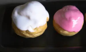 Deux petits choux garnis, l'un d'un glacage sucre glace blanc, l'autre d'un glacage rose.