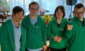 Quattro ragazzi con sindrome di Down, vestiti con felpe verdi, sorridono e posano per una foto.
