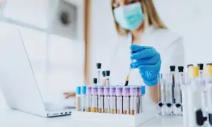 Laborantka w maseczce i rękawiczkach przygotowuje próbki krwi do analizy. Czas oczekiwania na wyniki badań krwi zależy od laboratorium.