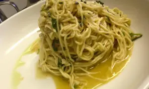 Un piatto di spaghetti aglio olio e peperoncino cremosi, conditi con prezzemolo fresco e un filo d'olio d'oliva.