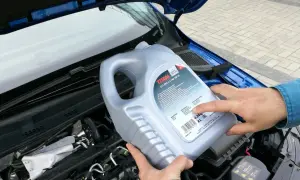 Osoba trzymająca kanister oleju silnikowego TITAN GT1 PRO C-3 SAE 5W-30 nad silnikiem. Czy można mieszać oleje silnikowe? Sprawdź specyfikację!