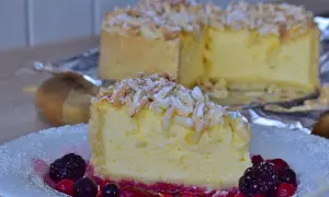 Una fetta di torta di riso ricetta originale, guarnita con mandorle e frutti di bosco, su un piatto bianco.