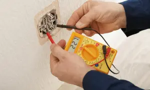 Elektryk mierzy napięcie w gniazdku. Wynik 227V sugeruje, że słaby prąd w domu to nie problem, a prawidłowe działanie instalacji.