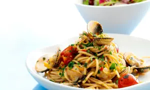 En tallrik med spaghetti vongole, toppad med färska musslor, körsbärstomater och persilja. En härlig italiensk rätt.