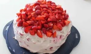 En himmelsk jordgubbstårta, täckt med fluffig grädde och generöst toppad med färska, hackade jordgubbar. En dröm för alla sötsugna!