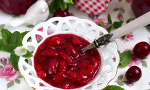 Aksamitna frużelina z wiśni w ozdobnej miseczce, ozdobiona miętą i świeżymi owocami.