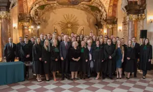 Grupa prawników w togach stoi w ozdobnym wnętrzu.