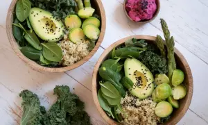 Två skålar med nyttig mat: quinoa, spenat, grönkål, avokado, brysselkål och sparris. En liten skål med rosa röra.