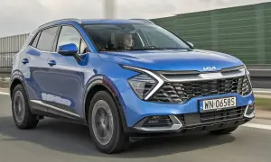 Niebieska, nowa Kia Sportage z kierowcą za kierownicą jedzie po drodze.