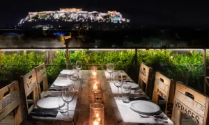 Gedeckter Tisch mit Blick auf die beleuchtete Akropolis bei Nacht.