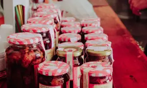 Słoiki z przetworami, w tym galaretką owocową, stoją w rzędzie. Zastanawiasz się, ile może stać galaretka owocowa w lodówce? Te domowe smakołyki wyglądają apetycznie.