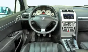Wnętrze Peugeot 407 2.0 HDI. Widok na deskę rozdzielczą, kierownicę, dźwignię zmiany biegów i siedzenie kierowcy.