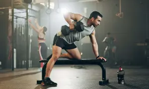 Mann trainiert im Fitnessstudio mit Hanteln. Mit diesem Training macht er fett fett.