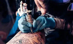 Artista creando un tatuaje de arte negro en la pierna.