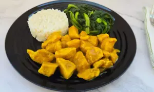 Piatto di pollo al curry con latte di cocco, riso bianco e verdure verdi saltate.
