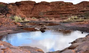 Wodopoje w Kings Canyon odbijają niebo, otoczone czerwonymi skałami i suchą roślinnością.