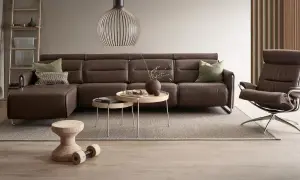 Braune Ledercouch mit grünen Kissen und Beistelltischen. Was passt zu brauner Couch? Helle Holztöne und natürliche Materialien.