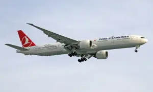 Samolot Turkish Airlines z wysuniętym podwoziem, gotowy do lądowania. W luku bagażowym czeka już bagaż pasażerów.