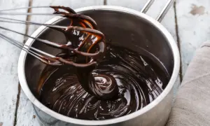 Fouet mélangeant du chocolat noir brillant dans une casserole, étape clé pour le tempérage.