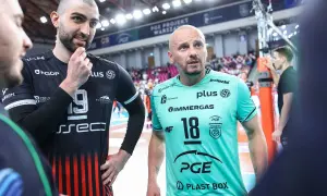 Siatkarze w strojach klubowych, jeden z nich z numerem 19, drugi z 18. W tle trybuny i siatka. Czy to aktualny mistrz świata w siatkówce?