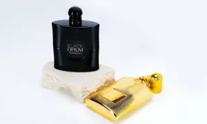 Elegancki flakon Black Opium 90 ml na kamiennej podstawie obok złotego flakonu.