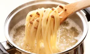 Spaghetti fraîchement cuits à l'italienne, retirés d'une casserole d'eau bouillante avec une cuillère en bois.
