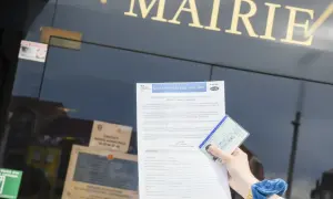 Main dans la main, une carte d'identité française et un formulaire de demande de changement de nom de famille sont présentés devant la mairie. Un geste pour de fautereau vassel.