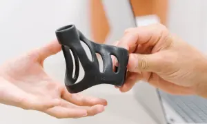 Eine Hand reicht eine schwarze Schiene, die zur Behandlung eines Schnappfingers dient, einer anderen Hand.