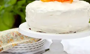 En saftig glutenfri morotskaka med vit frosting och strimlade morötter som dekoration. Perfekt för fikat!