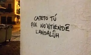 Graffiti en una pared con **expresiones sevillanas**: "Cateto tú que no'ntiende l'andalúh".