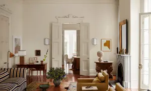 Soggiorno elegante con divani color ocra e un raffinato abbinamento colori crema. Tavolino in legno grezzo e tappeto decorato.