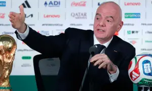 Prezydent FIFA, Gianni Infantino, gestykuluje podczas konferencji prasowej obok Pucharu Świata i piłki.