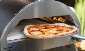 En pizza med tomatsås och ost bakas i en ugn på en pizzasten eller pizzastål.
