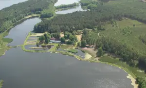 Agroturystyka Wilcze Doły: malowniczy krajobraz z jeziorami, lasami i zabudowaniami. Idealne miejsce na wypoczynek.