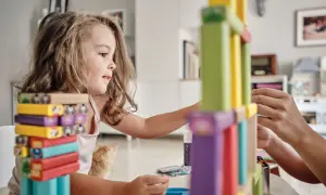 Niña concentrada construyendo con bloques de colores, disfrutando de juegos de habilidad para niños.