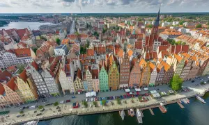 Gdańsk podział na dzielnice: widok z lotu ptaka na kolorowe kamienice przy Motławie, z łodziami i statkami.