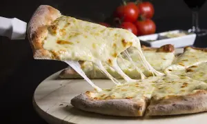 Kawałek pizzy z ciągnącym się serem, podniesiony łopatką.