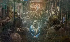 Młoda kobieta w dżinsowej kurtce stoi pośród tłumu, jej wyraz twarzy zdradza strach.