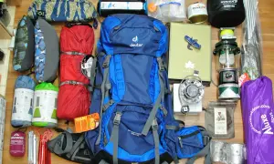 Alles, was man braucht für Camping: Rucksack, Schlafsäcke, Isomatten, Kocher, Lampe, Zeltstangen, Tasse und mehr.