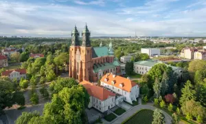 Widok na Ostrów Tumski z dominującą katedrą. Wokół zieleń drzew i zabudowania miejskie.