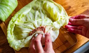 Ręce zwijają gołąbki z farszem mięsnym w liście kapusty. Idealny przepis na gołąbki na 1kg mięsa.