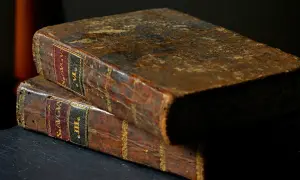 Dwie stare, skórzane księgi, jedna na drugiej. Na grzbietach widoczne napisy, sugerujące zawartość, być może mądrość Salomona z Biblii.