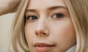 Zbliżenie na twarz młodej kobiety z blond włosami. Zastanawiasz się, ile rzęs wypada dziennie?