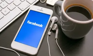 Telefon z Facebookiem, klawiatura i kawa. Dowiedz się, jak założyć konto szkoły na Facebooku, by być bliżej uczniów.