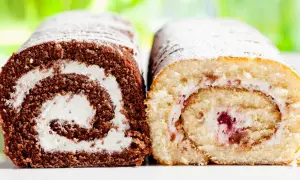 Zwei Biskuitrollen, eine Schoko- und eine helle Variante, mit Puderzucker bestäubt. Landfrauen-Kunstwerke, die zum Genießen einladen.