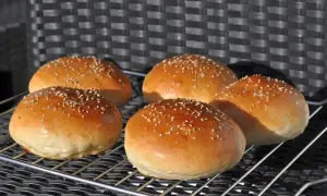 Fünf goldbraune Burger Buns mit Sesam, frisch gebacken nach einem tollen burger buns rezept.
